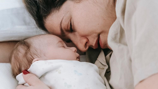 Maman couché sur un lit tenant son nouveau né dans les bras