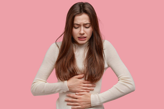 Femme se tenant le ventre avec ces deux mains en souffrance