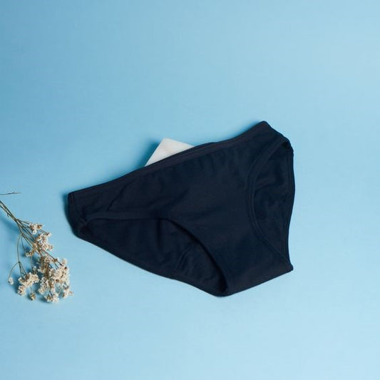 Culotte menstruelle noire déposée sur un support bleu