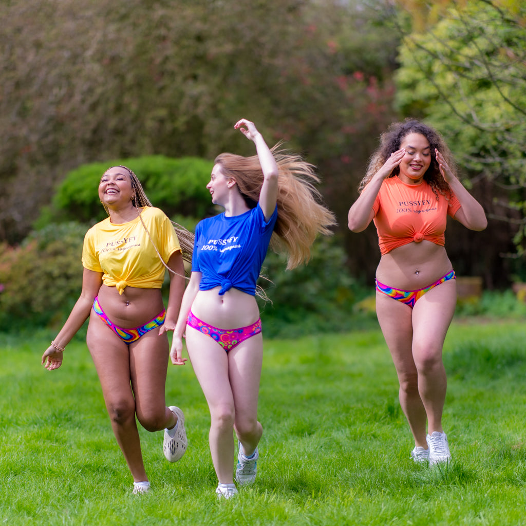 Trois jeunes filles marchant dans un jardin portant les culottes menstruelles psyché pop et disco de la marque Pussyfy, fabrication Belge