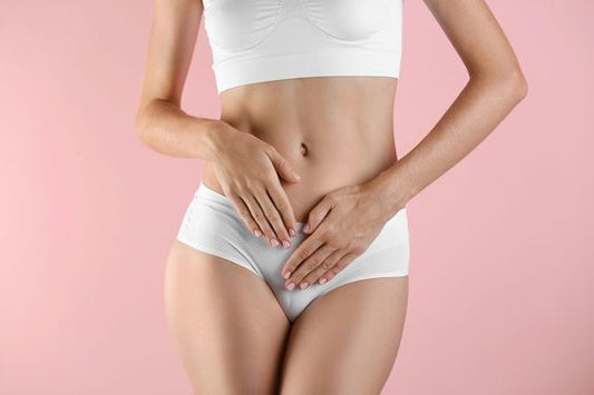 Le cours d'une femme en culotte blanche menstruelle et t-shirt blanc court. Mettant les deux mains sur son ventre