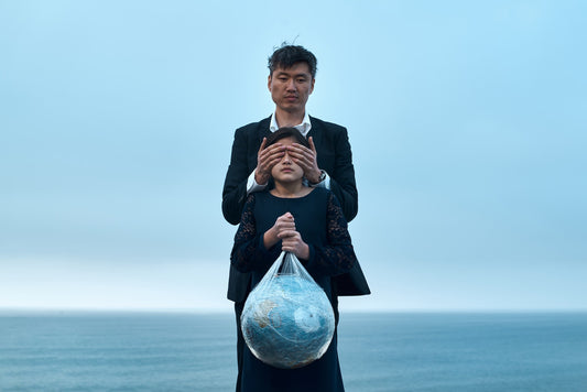 Une papa et sa fille sur la plage tenant une planète dans les mains entourée de plastique