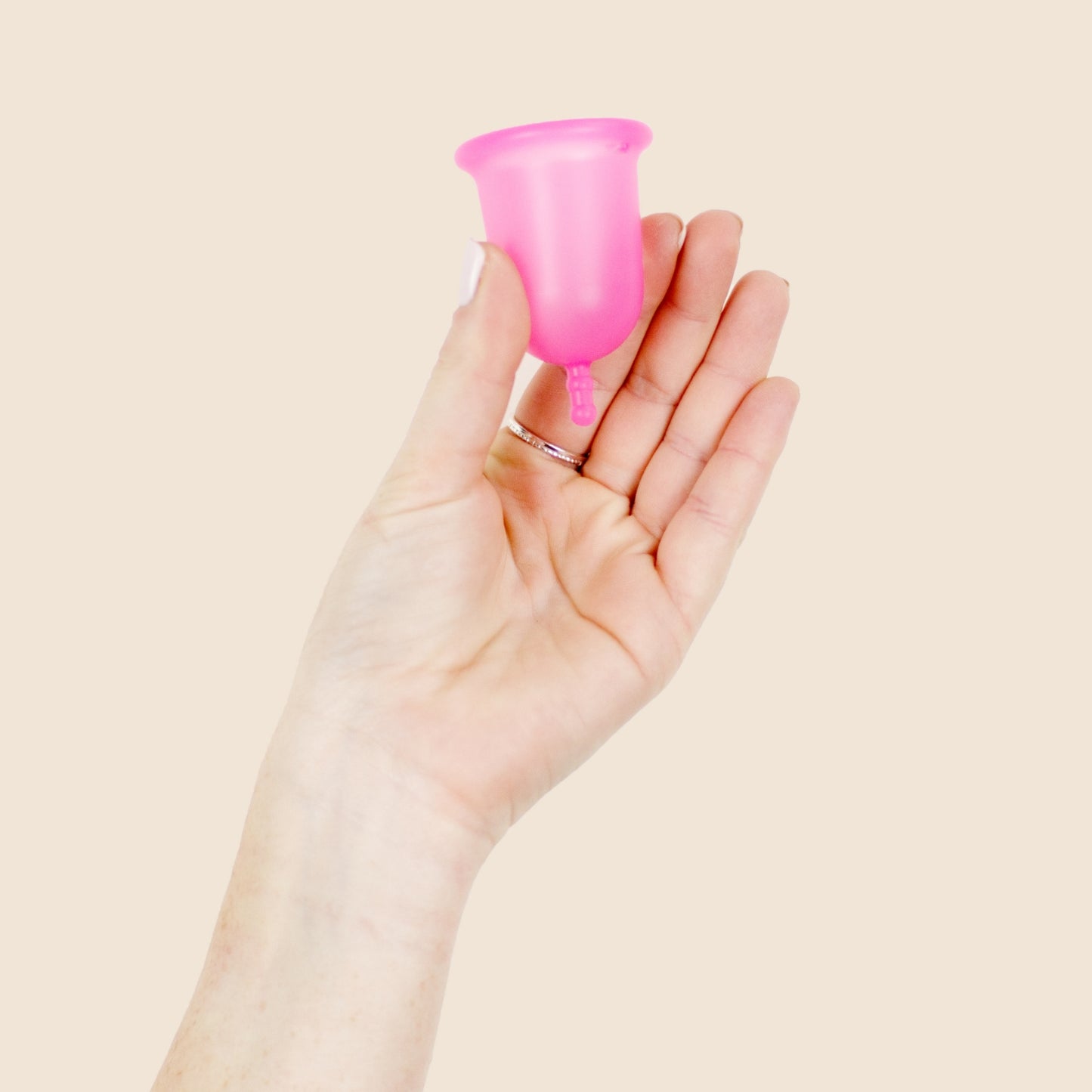 Une main tiens la cup menstruelle rose souple de 27 ml la grande minote fabriquée en France. Silicone de grade médical platine